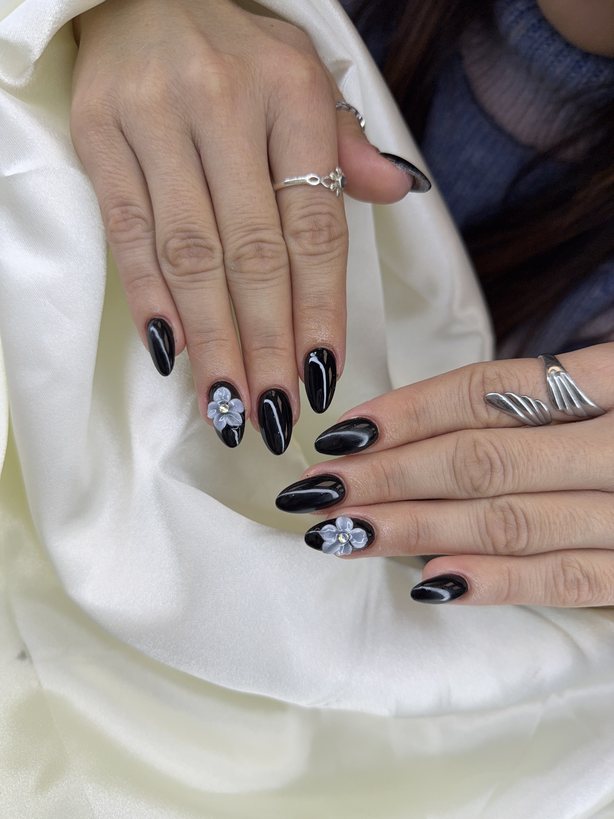 Zwarte nagels met witte bloemen en zilveren details
